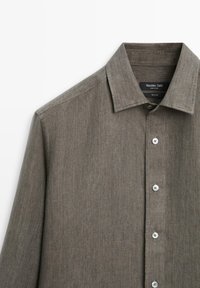 Herren-Hemd aus olivgrünem Leinen mit Knöpfen, Kragen, langen Ärmeln und Markenlabel an der Innenseite des Kragens.