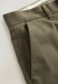 Pantalones verde oliva hechos de una tela suave, con un frente plisado, corte recto y un diseño de cinturilla limpia con un lazo.