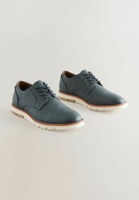 Dark blue leather shoes with a rounded toe, six eyelet lacing, and white rubber sole with beige accents. Smooth texture and minimal design.