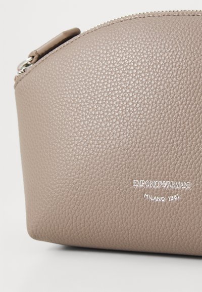Pungă din piele texturată de culoare maro deschis, cu formă rotunjită, închidere cu fermoar și detaliu logo embosat "Emporio Armani Milano 1981".