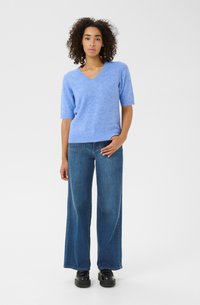 Lichtblauwe korte mouw v-hals trui met een zachte textuur, gecombineerd met een losse spijkerbroek in het blauw en zwarte platform schoenen.