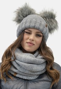 Gray knit beanie with two faux fur pom-poms and a textured design, paired with a matching gray knitted scarf. Leather accent tag included.