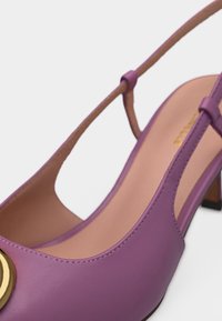 Μωβ δερμάτινο πέδιλο με λουράκι στη φτέρνα, διακοσμημένο με χρυσό κυκλικό στολίδι και μπεζ εσωτερική σόλα.