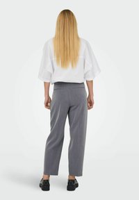 Šedé kalhoty s vysokým pasem a širokými nohavicemi s jemným proužkovaným vzorem, spárované s volnou bílou košilí. Minimalistický design, elegantní vzhled.