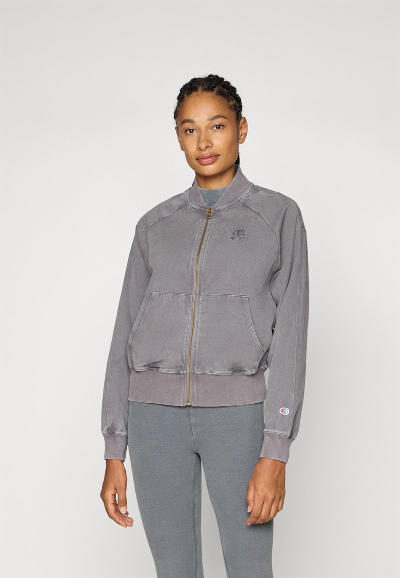 Gray zip-up jacket made of soft fabric, featuring a stand-up collar, side pockets, and ribbed cuffs, with a small logo on the chest.