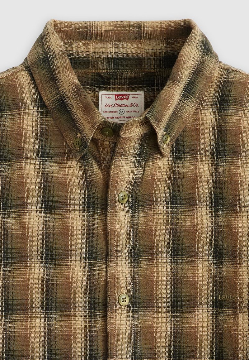Camisa de cuadros marrón con cuello tipo botón, dos botones frontales y una etiqueta con la marca "Levi's". Tejido texturizado con un patrón a cuadros.
