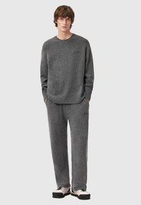 Szary zestaw bluzy i spodni dresowych, wykonany z miękkiego materiału. Posiada ściągacze na rękawach i w pasie oraz subtelne logo na piersi i nogawce.