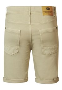 Beige farkkushortseissa on kääntölahkeet, joissa on kaksi takataskua ja ruskea etiketti vyötäröllä. Sujuva texture ja klassinen muotoilu.