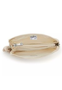 Kipling ritszak in beige stof met een gestructureerd oppervlak. Binnenin bevinden zich één ritsvak en twee open vakken. Decoratieve ritstrekkerr.
