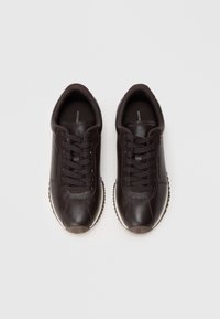 Zapatillas de cuero marrón con parte superior texturizada, puntera redonda, cordones tradicionales y suela blanca en contraste. Marca mínima en la plantilla.