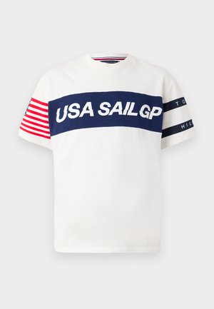 Balta marškinėliai su tamsiai mėlynomis horizontalinėmis juostelėmis, kuriuose raudonais ir baltais dideliais rašmenimis parašyta "USA SAILGP". Raudonos ir baltos juostelės ant rankovių. Paprasta apvalia apykakle.