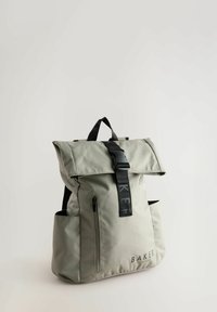 Sac à dos en textile gris avec un design à rabat, une sangle noire, un logo, une poche zippée à l'avant et deux poches latérales. Fini mat.