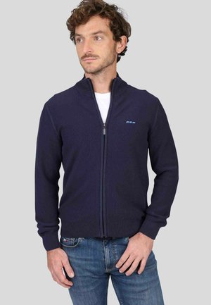 Pull-over zippé marine avec un design en tricot texturé, un col haut et une coupe slim, arborant un petit logo bleu clair sur le côté gauche.
