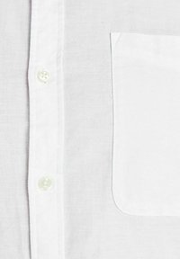 Weißes Baumwollhemd mit einer Knopfleiste, einer aufgesetzten Tasche und glatter Textur. Leichter Stoff mit feiner, subtiler Webart.