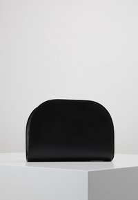 Borsa a mano in pelle nera con una texture liscia, parte superiore curva e senza hardware visibile. Design minimalista, forma rettangolare e dimensioni compatte.