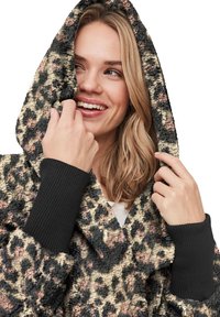 Gezellige hoodie-jack in een getextureerd, luipaardprintpatroon met tinten zwart, roze en crèmetint. Kenmerkt geribbelde zwarte manchetten en capuchon.