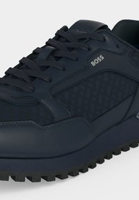 Σκούρο μπλε αθλητικό παπούτσι BOSS με υφή στην επάνω επιφάνεια, κορδόνια και μαύρη λαστιχένια σόλα με ανάγλυφα.