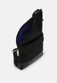 Borsa in tessuto nero con una texture liscia e un design angolare. Presenta una chiusura con zip, un interno blu e un pannello inferiore a contrasto in nero.