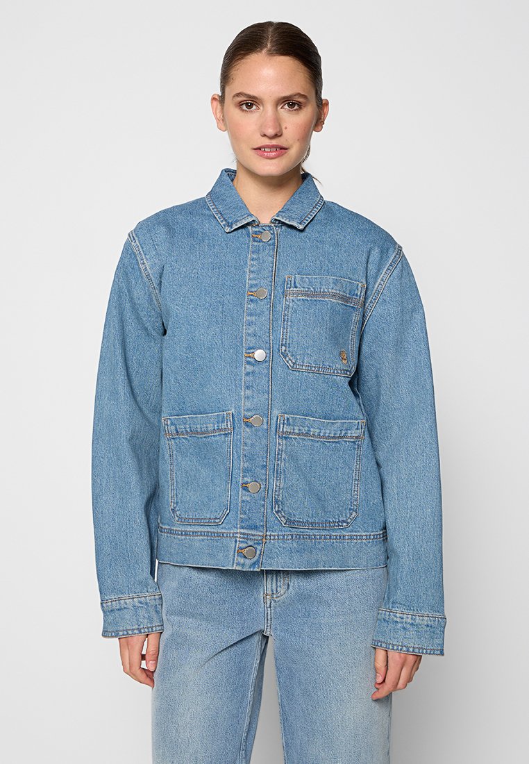 Giacca in denim azzurro chiaro con colletto, bottoni frontali e due tasche sul petto. Presenta cuciture a contrasto e una vestibilità rilassata.