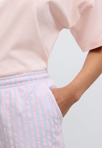 Ροζ βαμβακερό μπλουζάκι με κοντά μανίκια συνδυασμένο με μπλε και ροζ κοντά παντελόνια με ρίγες, ελαστική μέση και πλαϊνές τσέπες.