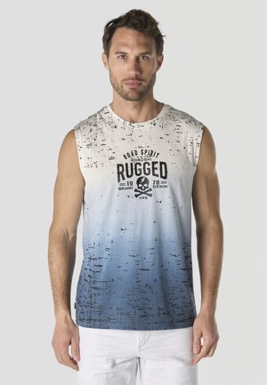 Hombre con cabello corto y castaño que lleva una camiseta sin mangas blanca con degradado azul, con el texto "Rugged" y un gráfico de calavera, de pie frente a un fondo liso.
