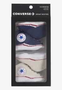 Två par bebisboots i marinblått och gräddvitt med röda detaljer. Varje par har en gummiytpatch med en stjärna. Förpackade i en genomskinlig låda.