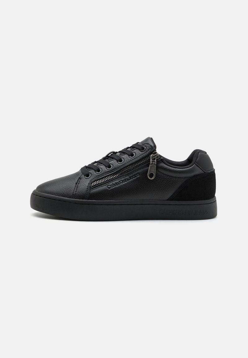 Baskets basses en cuir noir avec fermeture éclair latérale, lacets noirs, détails texturés et marquage subtil sur la semelle et le panneau latéral.