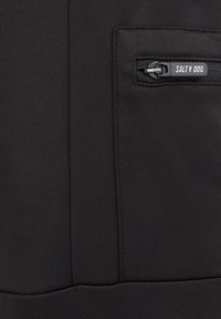 Giacca in tessuto nero con tasca sul petto con zip e la scritta "SALTY DOG" in rilievo. Texture liscia con dettagli di cucitura strutturata.