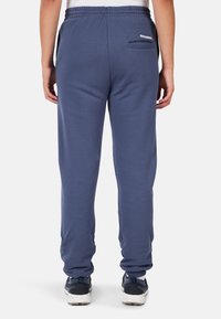 Niebieskie spodnie dresowe z elastyczną talią na sznurek, bocznymi kieszeniami i kieszenią z tyłu z małym logo. Miękka tkanina o luźnym kroju.