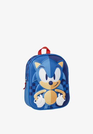 Blue backpack featuring a 3D design of a character with large eyes and a smiling expression, red handle, and checkered pattern.