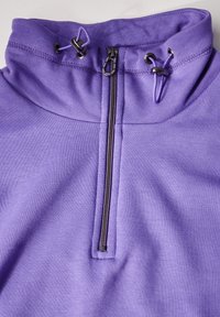 Felpa alta viola in tessuto morbido con zip frontale. Presenta stringhe regolabili e una texture liscia con un design aderente.