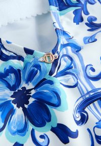 Gėlėmis margintas audinys mėlynų ir žydrų atspalvių su balta fone. Turi apvalų kaklo iškirpimą ir rožinio aukso užsegimą.