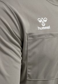 Grå atletisk t-shirt med en glat tekstur, der har en forlommer og et hvidt Hummel-logo på brystet.