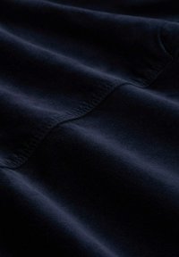 Dunkelblaues Gewebe mit glatter Textur, das subtile Wellen und genähte Kanten aufweist, wodurch das weiche und dicke Material betont wird.