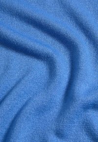 Modrá pletenina s hladkým povrchem, s pravidelným vzorem jemných stehů a drobnou elastickostí, vytvářející jemné vlnění.