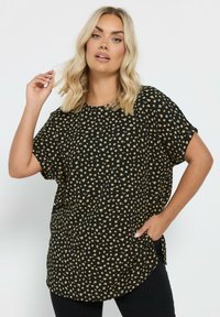Top nero con motivo a pois dorati, vestibilità ampia, scollo rotondo, maniche corte, fessure laterali, tessuto leggero.
