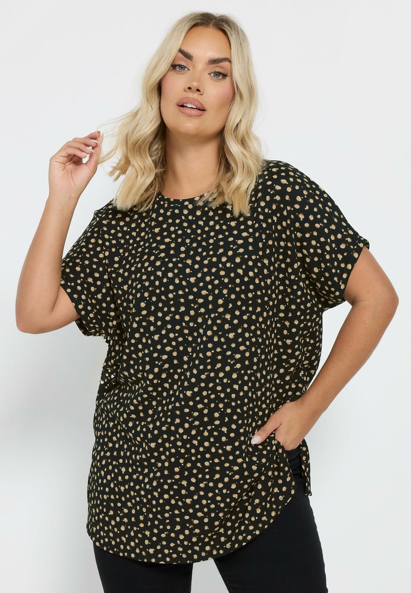 Top nero con motivo a pois dorati, vestibilità ampia, scollo rotondo, maniche corte, fessure laterali, tessuto leggero.