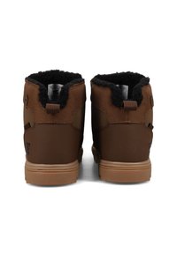 Barna téli csizma pár fekete bolyhos béléssel és bézs gumitalppal, hátulról nézve, fehér háttér előtt.