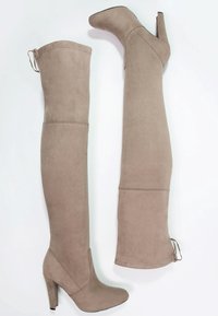 Bottes en daim beiges hauteur genou avec talons carrés, bouts ronds et fermetures éclair à l'arrière, présentées côte à côte sur un fond blanc.
