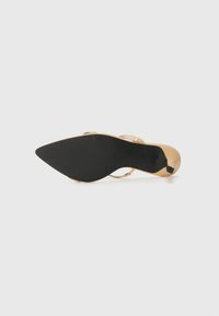 Scarpa con tacco alto beige, con retro aperto, punta affusolata e suola in gomma nera. Presenta sottili cinturini sul piede e sulla caviglia.