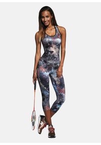 Dopasowany strój sportowy w kolorowym, abstrakcyjnym wzorze; bezrękawnik w połączeniu z krótkimi legginsami. Brązowe buty sportowe i rakieta do badmintona.