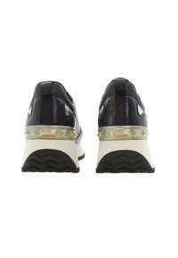 Czarne sneakersy z teksturowanym wykończeniem, z grubą białą podeszwą i przezroczystym, ćwiekowanym akcentem na obcasie. W zestawie z pętelką z tyłu.