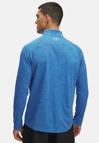 Langärmliges Sportshirt in Blau mit einem strukturierten, melierten Muster. Mit hohem Kragen und Logo auf der Rückseite. Leichter Stoff.