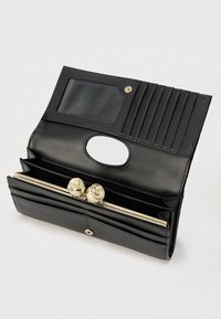 Crna kožna novčanik teksturiranog završetka, s prozirnim utorom za ID, višestrukim utorima za kartice i zatvaranjem zlatne boje. Unutrašnjost uključuje prostor za novčiće.