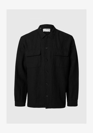 Camisa negra de botones con mangas largas, hecha de una tela texturizada. Cuenta con dos bolsillos en el pecho y un cuello clásico.