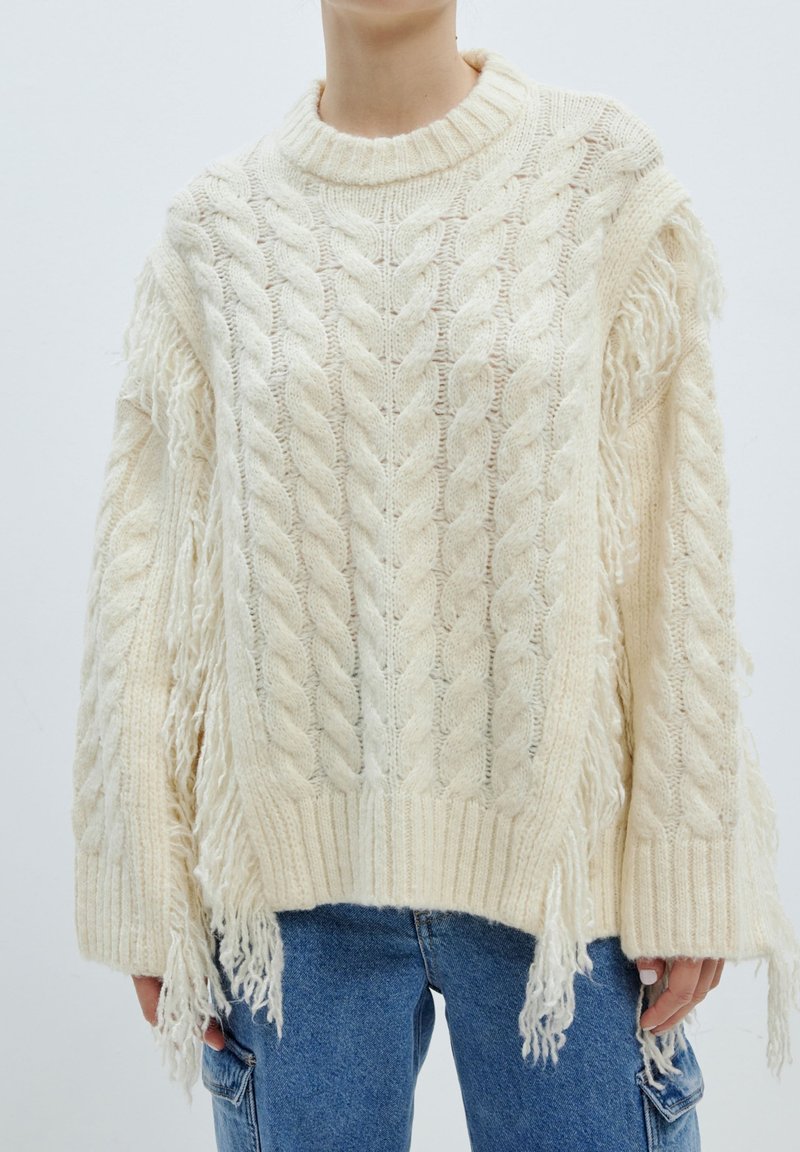 Flauschiger, cremefarbener Strickpullover mit Kabelmuster und fransigen Akzenten an den Ärmeln und dem Saum, hochgeripptem Ausschnitt und lockerer Passform.