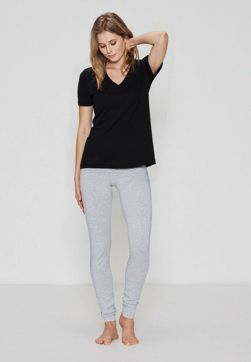 Sort V-hals T-shirt parret med lysegrå leggings. Stoffet er blødt, med et tætsiddende design og ankel-længde.