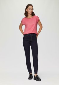 Roze satijnen top met korte mouwen, gecombineerd met donkerblauwe skinny jeans en zwarte schoenen, met een klassieke pasvorm en minimalistisch ontwerp.