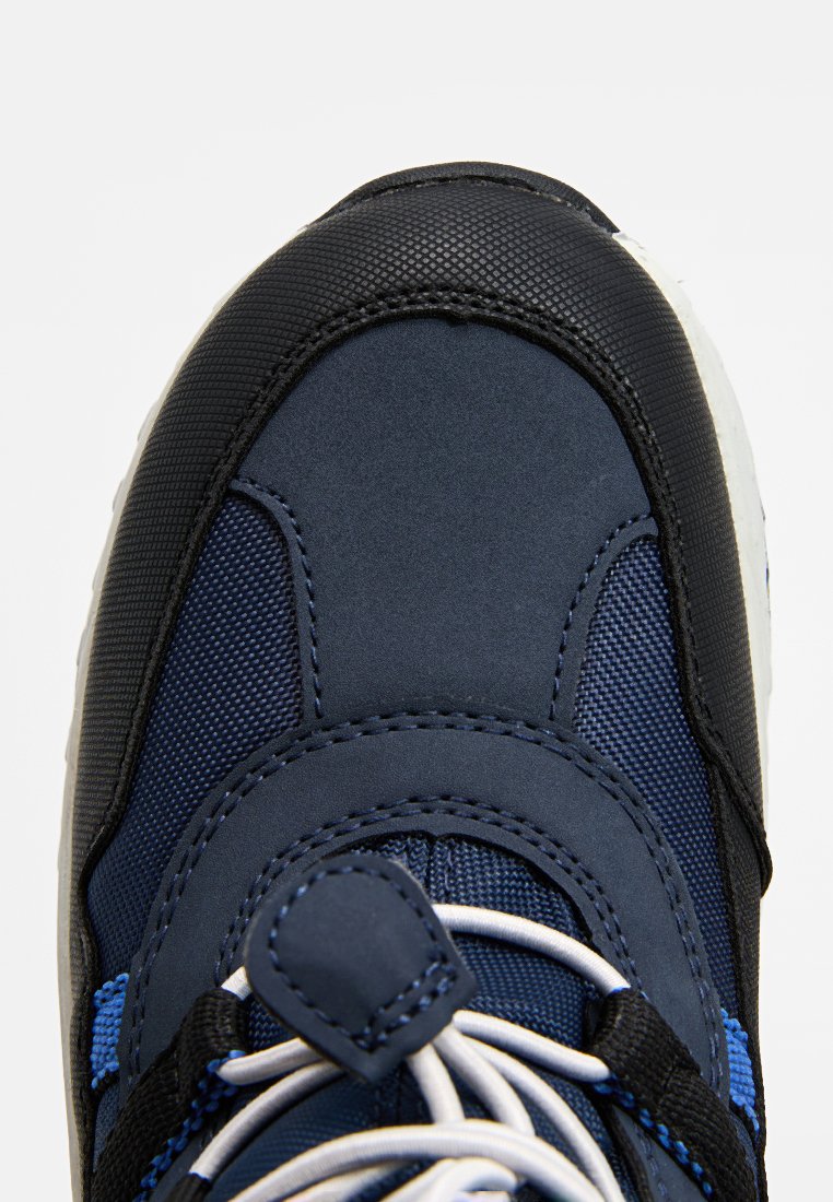 Marineblaue Sportschuhe mit einer strukturierten schwarzen Oberseite, Netz-Einsätzen, weißer Laufsohle und kontrastierenden blauen Akzenten sowie traditioneller Schnürung.