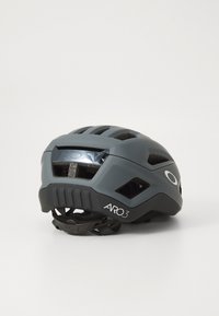 Grauer Fahrradhelm mit matter Oberfläche, Belüftungsöffnungen, verstellbarem Riemen und einem Logodetail an der Seite.